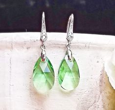 💎Handcrafted with gorgeous 16mm peridot green CRYSTALLIZED™ - Swarovski Elements teardrop pear shape crystals 💎Luxurious cubic zirconia-decorated ear wire 💎Crafted with high-quality, tarnish-free original rhodium plating 💎Hypoallergenic Beautiful and gorgeous dangle earrings, perfect for daily fashion or formal occasions! ❗️Crystal colors may appear slightly different depending on your computer monitor settings❗️ Free shipping for U.S. buyers on orders $35 or more!  All of my items are craft Green Teardrop Crystal Earrings, Green Crystal Teardrop Earrings, Green Pear-shaped Teardrop Earrings, Green Teardrop May Birthstone Earrings, Green Teardrop Earrings For May Birthstone, Dangle Silver Earrings, Crystal Colors, Peridot Green, Green Peridot