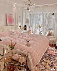 a bed with pink comforter and pillows in a bedroom next to a chandelier