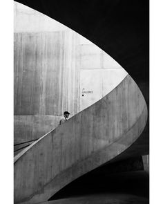 black and white photograph of a man walking up the side of a concrete structure with stairs