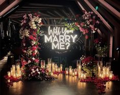 a wedding arch with candles and flowers on the floor in front of it that says will you marry me?