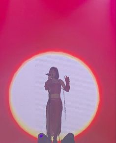 a woman standing on top of a stage in front of a red and yellow circle