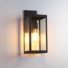 a light that is on the wall next to a white wall with a black frame