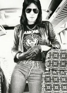 a woman wearing sunglasses and leather jacket standing next to luggage