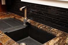 a kitchen sink with granite counter top and black faucet in the center,