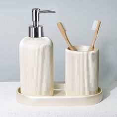 two toothbrushes and soap dispenser sitting on a white counter top