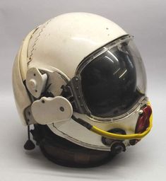 a white helmet with yellow wires attached to it's side and the face of an astronaut wearing a space suit