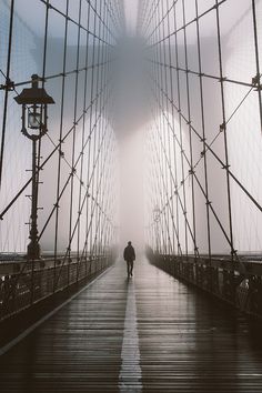 a person walking across a bridge in the fog