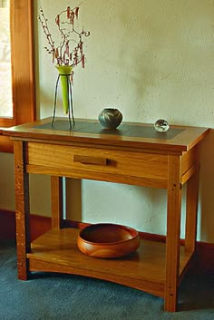 a small wooden table with a vase and bowl on it