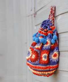 a crocheted bag hanging from the side of a building on a hook attached to a wall