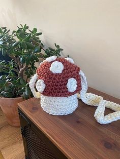 a crocheted mushroom bag sitting on top of a wooden table next to a potted plant