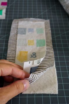 someone is cutting up fabric with scissors on a piece of cloth that has been cut into squares