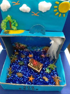 an open blue box filled with sand and sea life