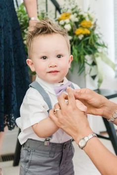 a little boy getting his tie put on by an adult