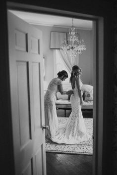 two women standing in front of a door and looking at each other's dresses