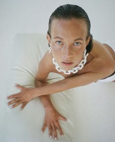 a woman laying on top of a white pillow with her arms stretched out to the side