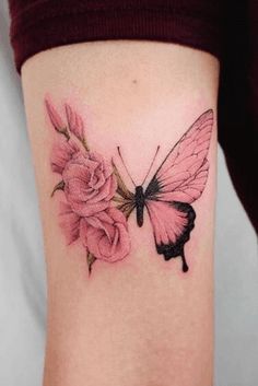 a small pink butterfly and flowers tattoo on the right side of the arm, with one flower in it's center