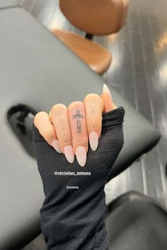 a woman's hand with a small cross tattoo on her left thumb and fingers