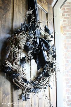 a wreath is hanging on the door with black ribbon around it and some dried twigs