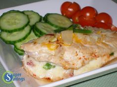 a white plate topped with chicken, cucumbers and tomatoes