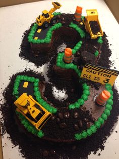 there is a cake that looks like the number 3 made out of dirt and construction equipment