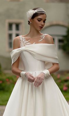 a woman in a white wedding dress with gloves on her hand and an off the shoulder top