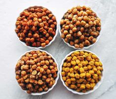 four bowls filled with nuts on top of a white countertop next to each other