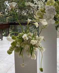 two white vases with flowers in them on a balcony