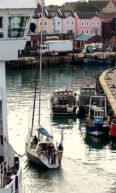 several boats are docked in the water near some houses and buildings on either side of the dock