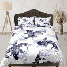 a bed with blue and white fish on the comforter, next to a lamp