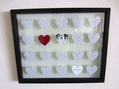 a shadow frame with hearts cut out of paper and pinned to the wall above it