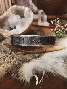 a close up of a ring on top of a piece of wood next to flowers