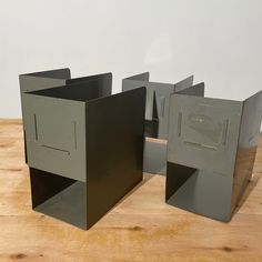 three metal boxes sitting on top of a wooden table next to each other, one with an opening in the middle