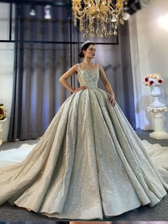 a woman standing in front of a chandelier wearing a silver dress with sequins on it