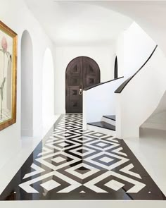 an entry way with black and white tiles on the floor, stairs and framed pictures