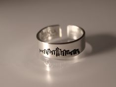 a silver ring with the word new york etched in black ink on it's side