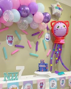 a birthday party with balloons, streamers and animals on the wall in front of it