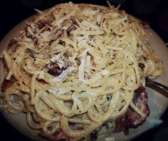 a plate full of pasta with meat and parmesan cheese on top, ready to be eaten