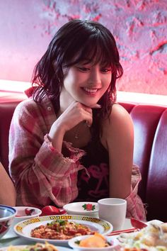 a woman sitting at a table with plates of food in front of her and smiling