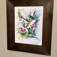 a painting hanging on the wall above a toilet in a bathroom with a wooden frame