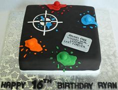 a birthday cake that is shaped like a book with paint splatters on it