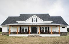 a white house with black shutters on the front porch and two large windows in the back