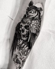 a black and white tattoo with an owl sitting on top of a skull surrounded by flowers