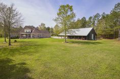 a large yard with lots of grass and trees in front of the house on a sunny day