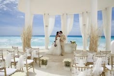 a newly married couple standing in front of an open air ceremony area at the beach