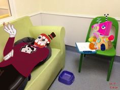 a person laying on a green chair next to a small table with a stuffed animal