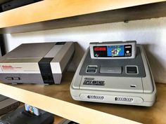 an old nintendo game system sitting on top of a shelf next to other electronic devices