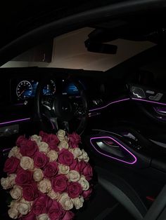 a bouquet of roses sits in the center console of a car, next to an illuminated steering wheel