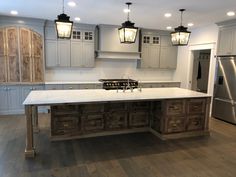 a large kitchen with an island in the middle and two pendant lights hanging from the ceiling