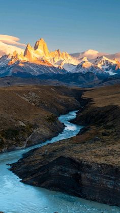 the mountains are covered in snow and have a river running through them, with water flowing between them