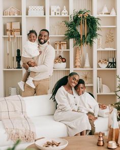 two adults and a child are sitting on a couch in the living room with christmas decorations